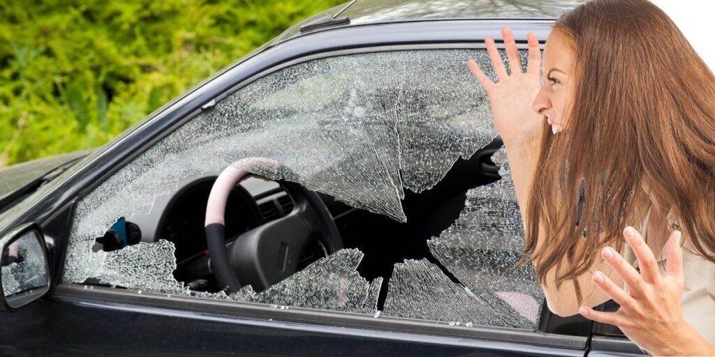 En bil med krossad ruta och en irriterad kvinna. Ägaren blev irriterad för att polisen krossat en bilruta för att rädda en hund. Det är inte kvinnan i texten på bilden